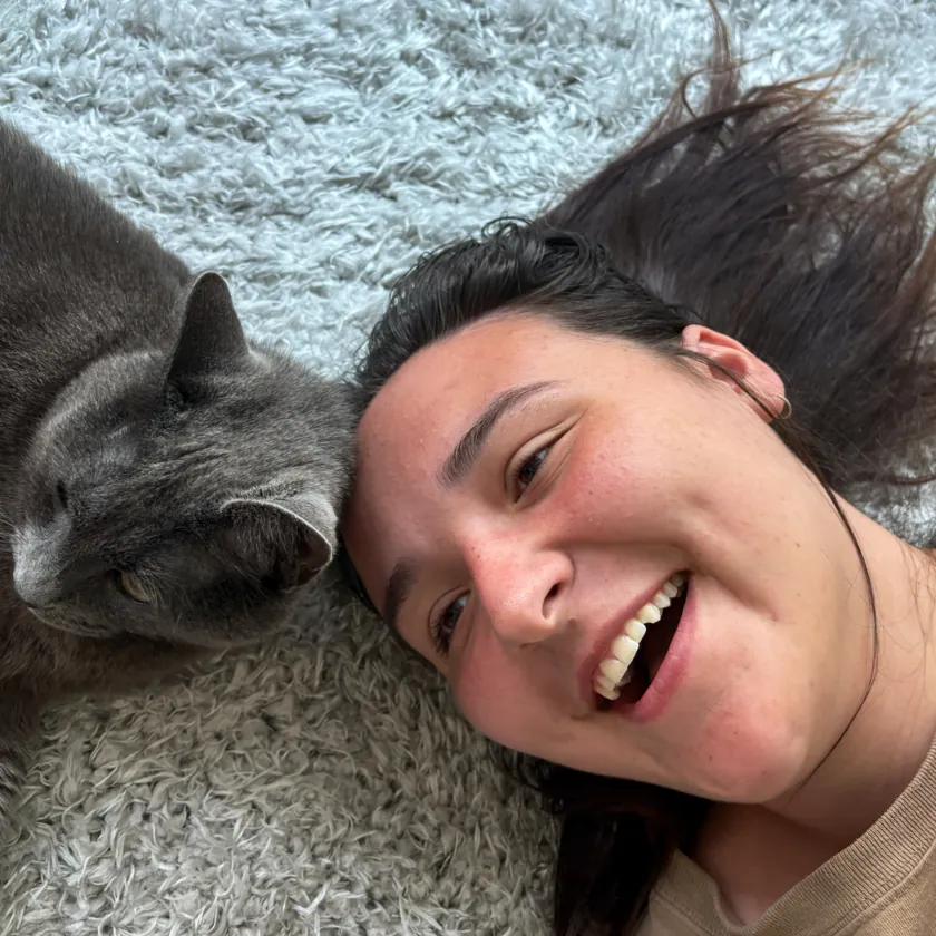 Elle lying on a rug next to a gray cat